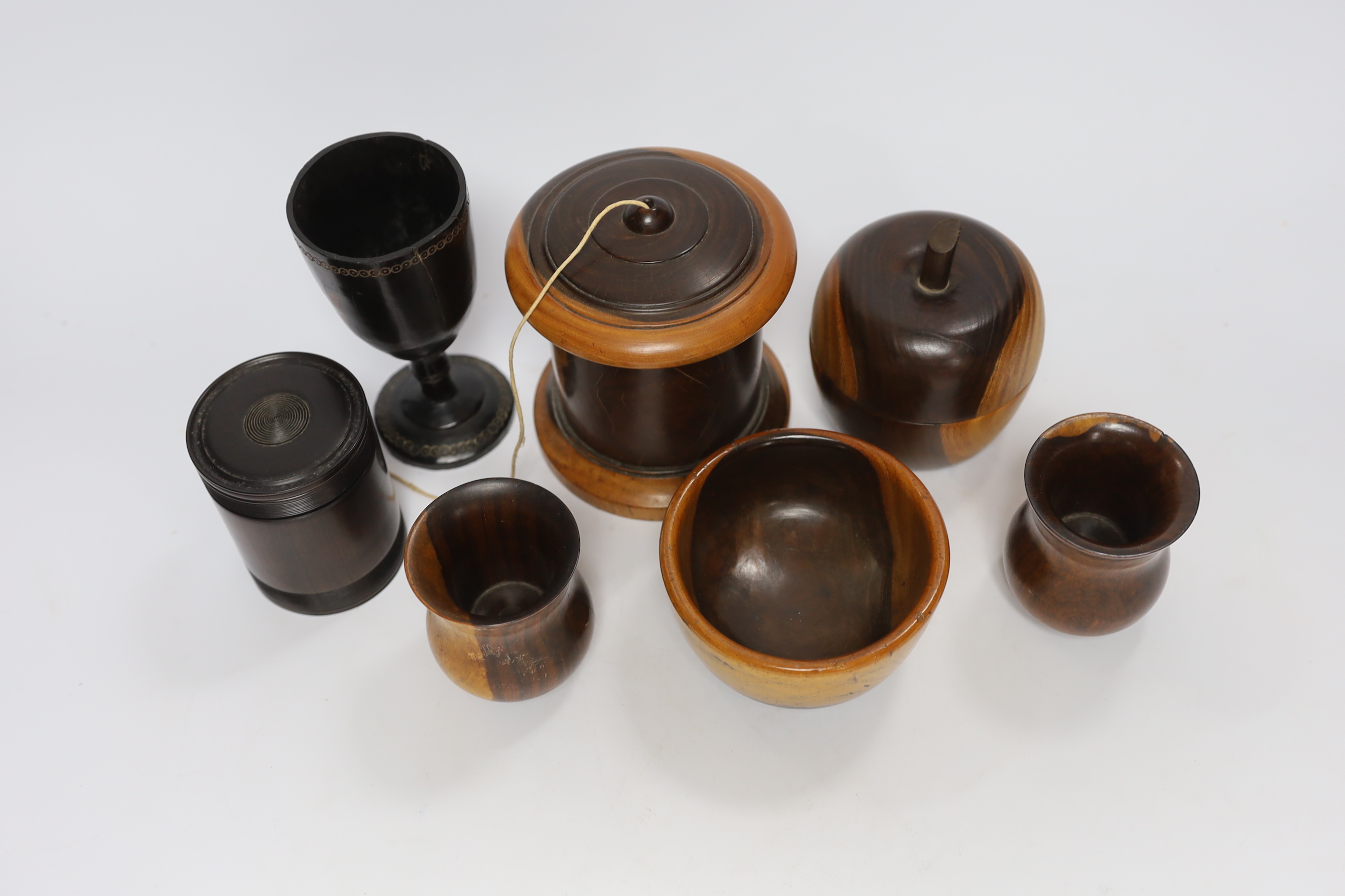 A collection of 19th/20th century lignum vitae vessels, including a turned string box and cover, an apple shaped box and cover, two vases, a mortar, a goblet and a box and cover (7)